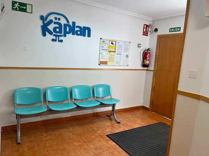 Sala de espera con sillas azules y pared blanca