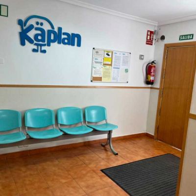 Sala de espera con sillas azules y pared blanca