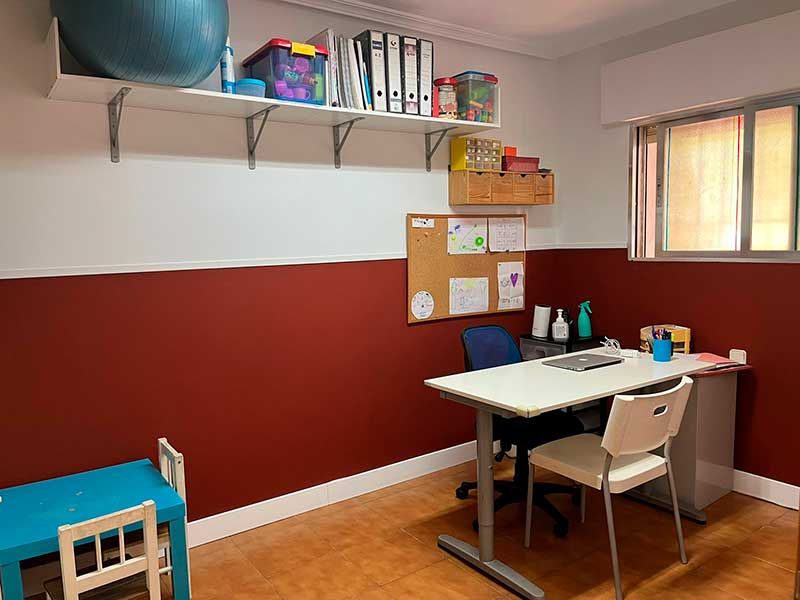 Despacho con pared rojiza y mesa